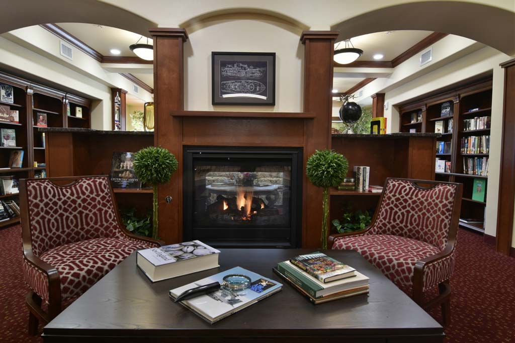 Ashton Gardens common area with fireplace and books