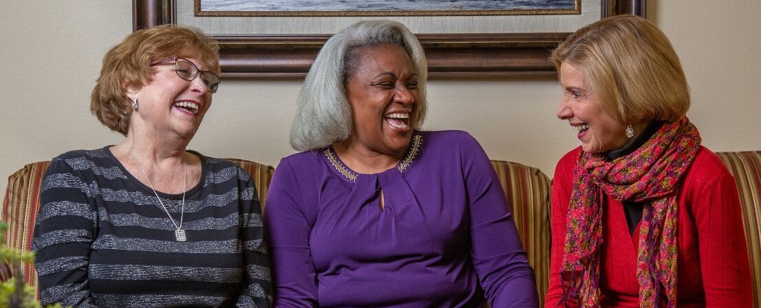 Hawthorn Senior Living. Chesterfield Heights. Three Senior Ladies Laughing on Couch.