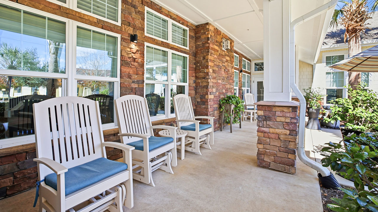 A row of chairs on a porch.