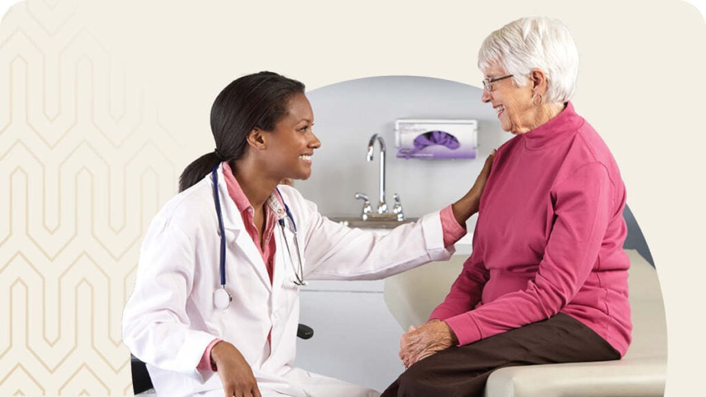 Senior sitting on examination table with doctor in front of her