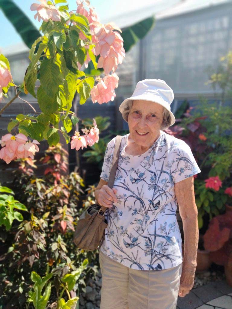 Senior standing next to tree with flowers