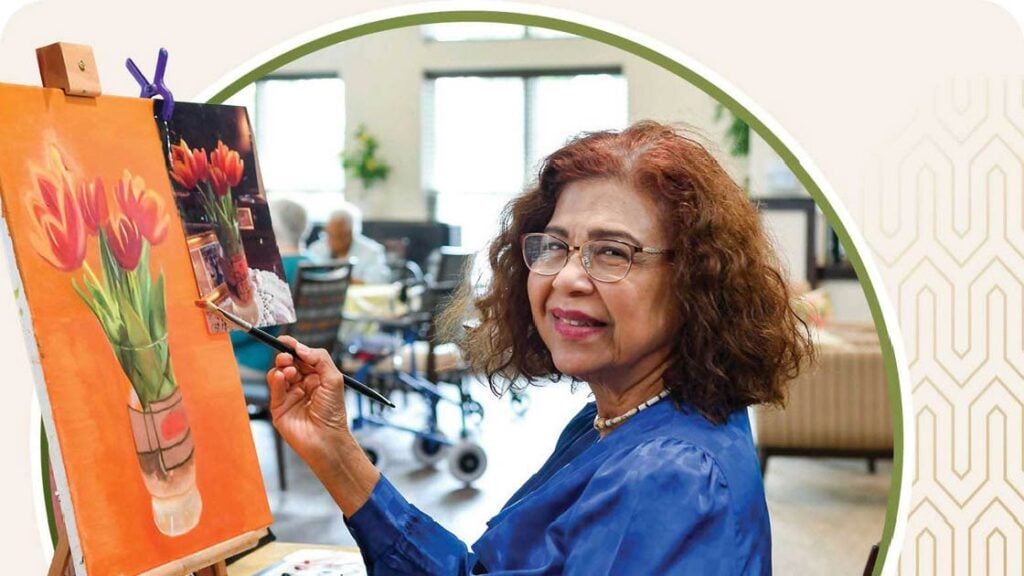 Senior woman painting flowers on canvas