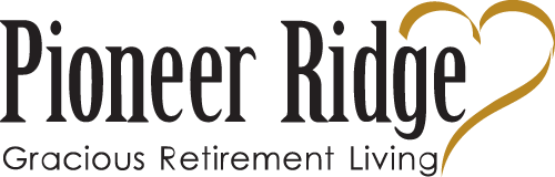 Logo with the text "Pioneer Ridge Gracious Retirement Living." The word "Pioneer Ridge" is in large, elegant font, and "Gracious Retirement Living" is in smaller, refined font. There is a gold heart shape integrated into the design.