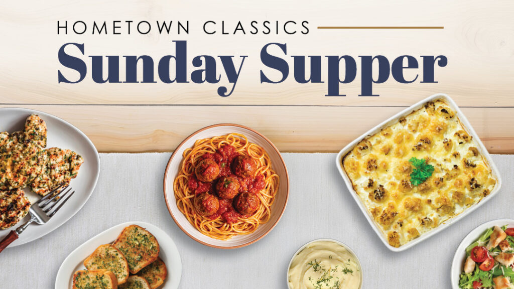 A table set with garlic bread, spaghetti and meatballs, cheesy casserole, chicken, and a bowl of dip, with the text “Hometown Classics Sunday Supper” above the food.