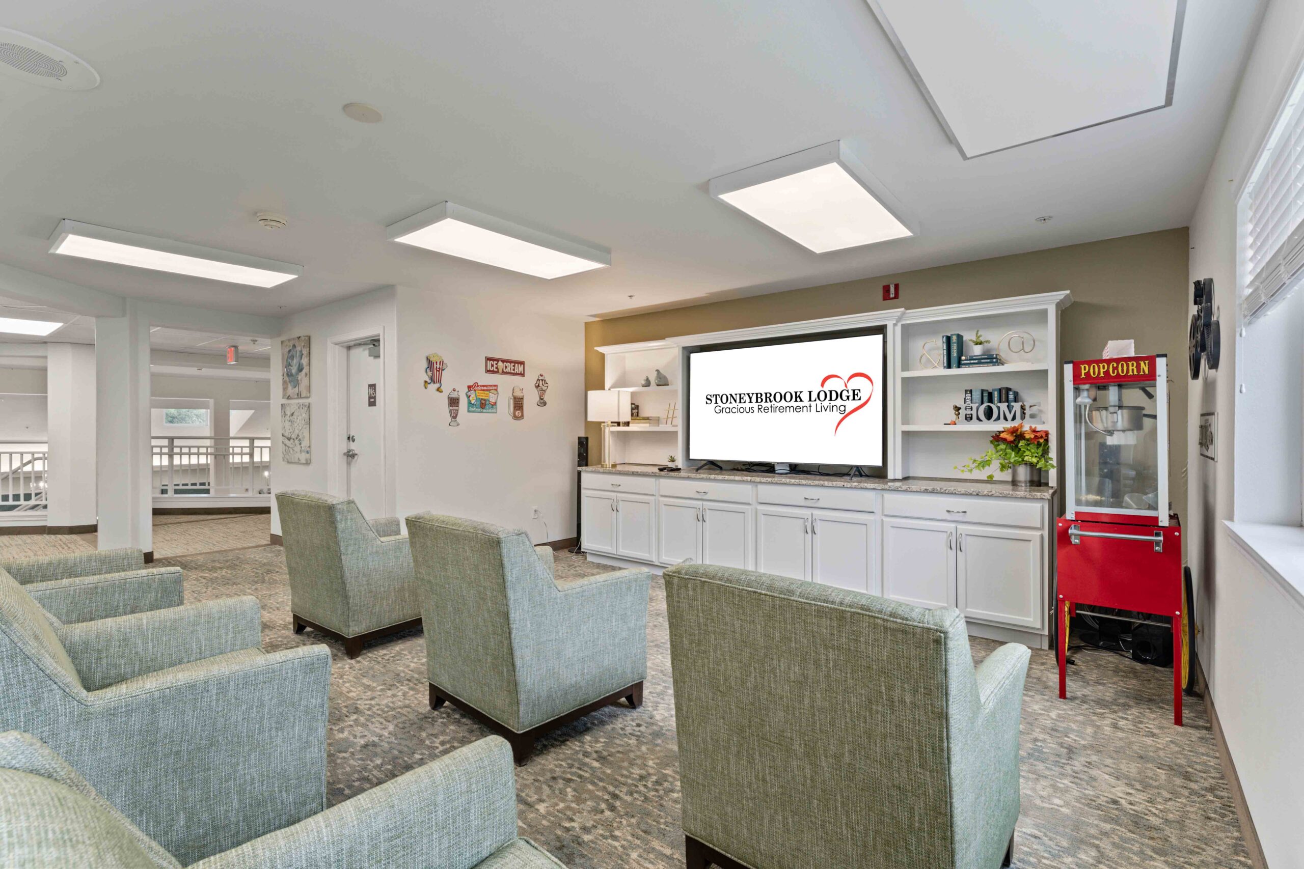 A cozy community room with a popcorn machine and a large, wall-mounted TV displaying 