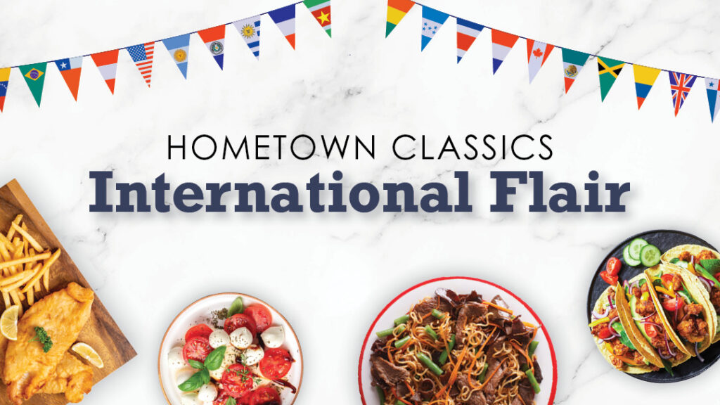 Plates of international dishes are shown below a banner of global flags. Text reads “Hometown Classics International Flair” on a white marble background.