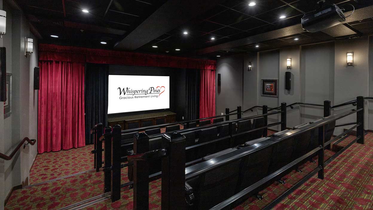 A small movie theater with elegant red curtains framing a screen displaying the text 