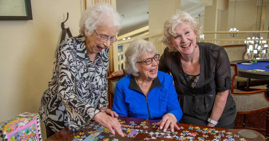 3 female senior residents putting together a puzzle