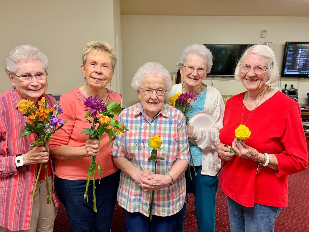 Smiling females standing with flowers in hands