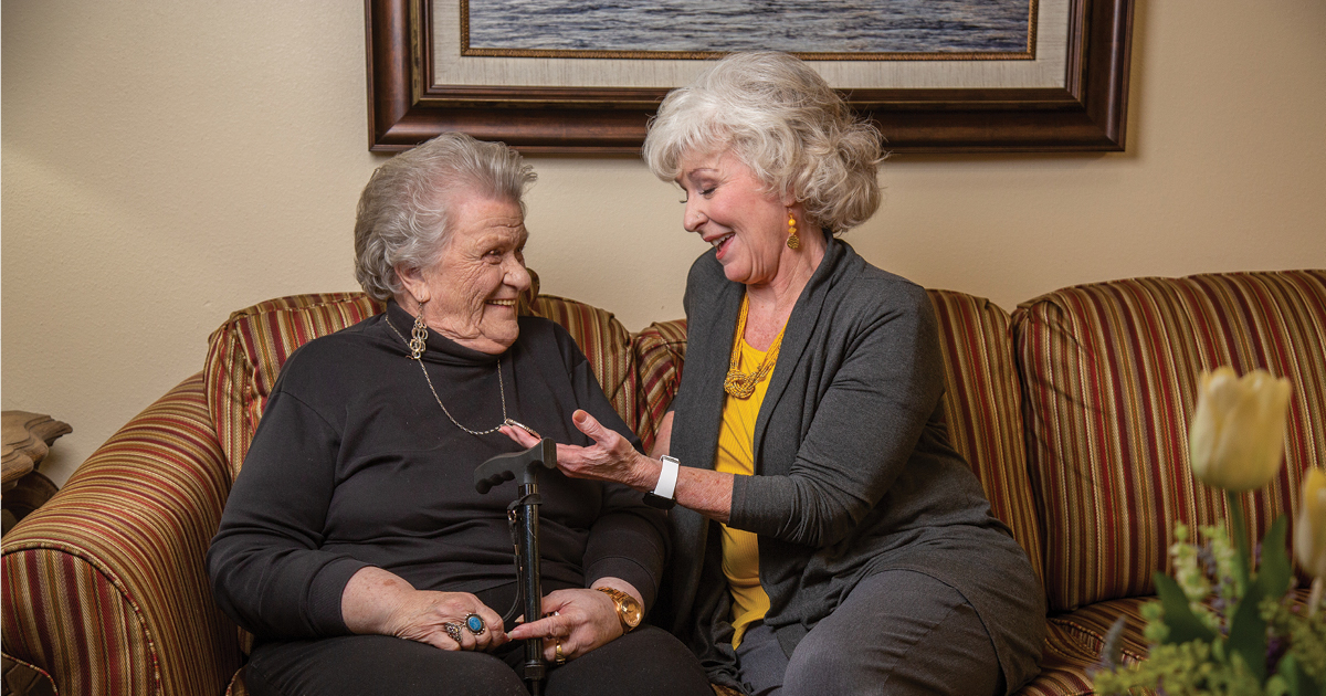 two senior women smiling on a couch