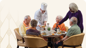 Chef and staff member serving group of seniors at dining table