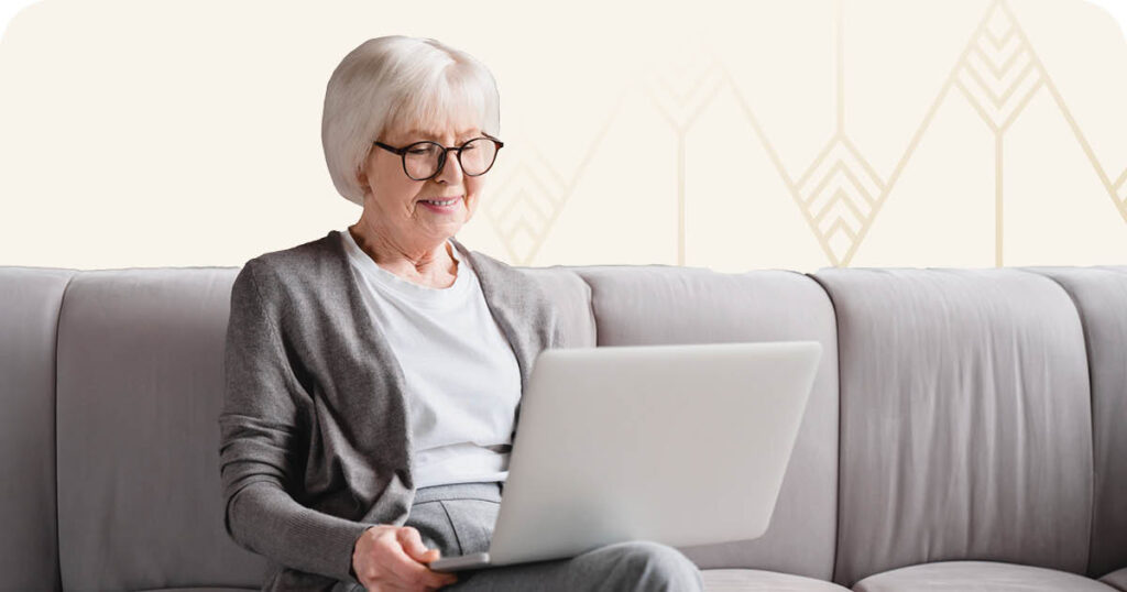 Senior woman sitting on the couch and working on laptop