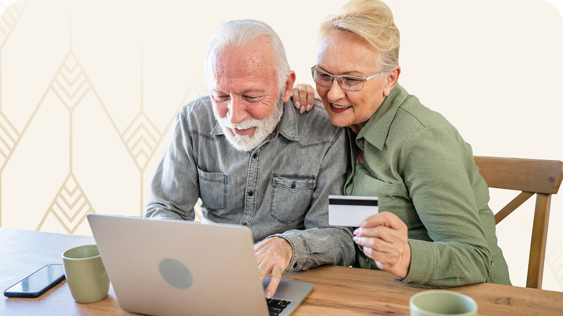 Senior couple looking at computer with credit card in hand