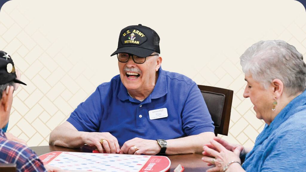 Three seniors playing a game at a dining table