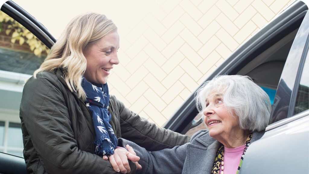 Woman helping senior woman out of a car
