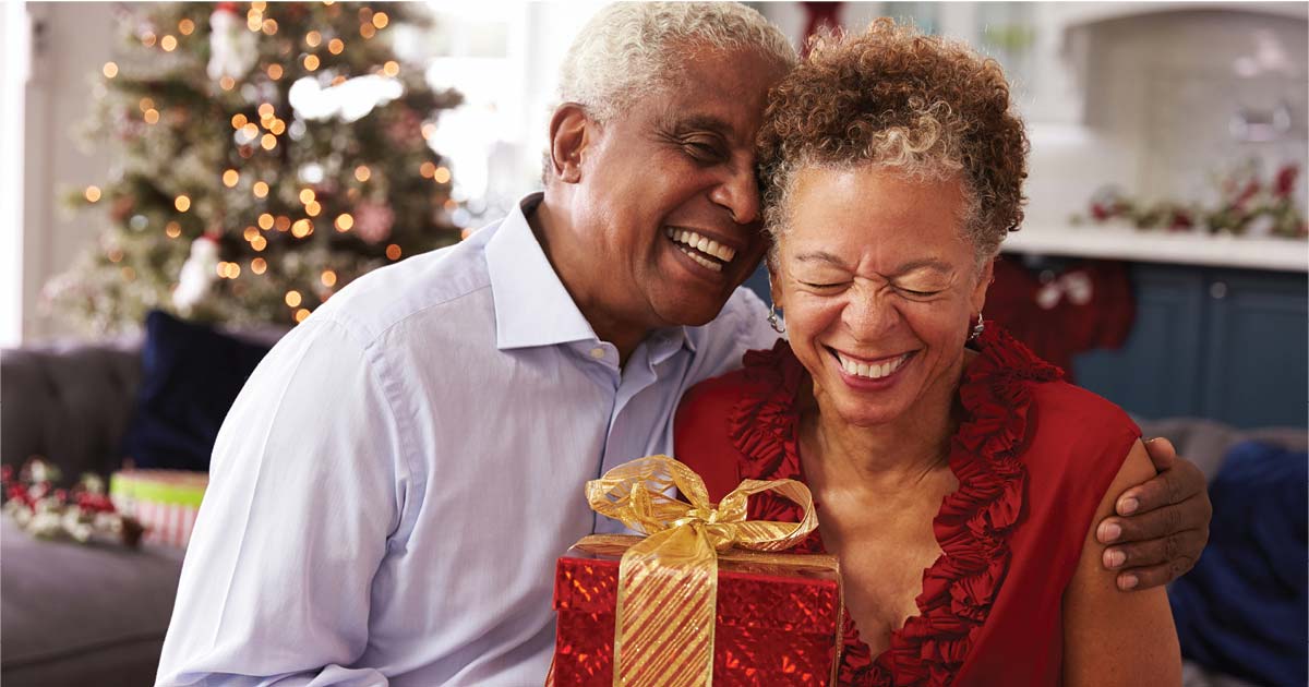 Senior couple hugging with a Christmas box
