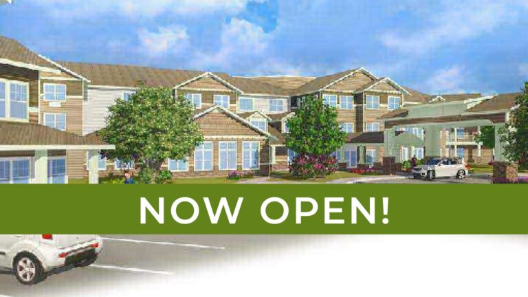 A visually appealing image of a modern residential complex with multiple buildings and landscaped greenery. The scene is bright with a partly cloudy sky. Overlaid on the image is a green banner with white text that reads, "NOW OPEN!.