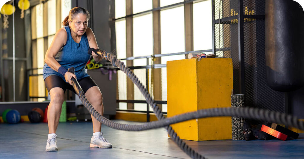 Senior woman using ropes in the gym
