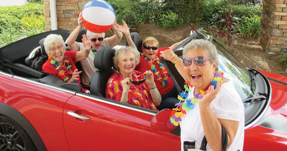 Seniors riding in red convertible